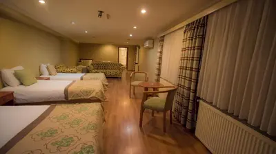 a hotel room with two beds and a table and chairs at Boyuguzel Termal Hotel in Bursa