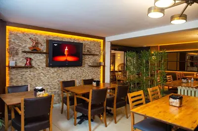 a restaurant with wooden tables and a tv on a brick wall at Emirtimes Hotel Kadıköy in Istanbul
