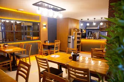 a restaurant with wooden tables and chairs and a kitchen at Emirtimes Hotel Kadıköy in Istanbul