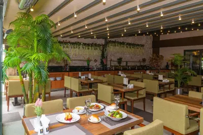 a restaurant with tables and chairs and palm trees at Land Park Hotel in Istanbul
