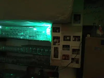 a bar with green lights on a shelf with glasses at Paris Hotel in Istanbul