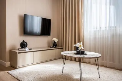 a living room with a table and a tv on a wall at Çırağan Apart Bosphorus in Istanbul