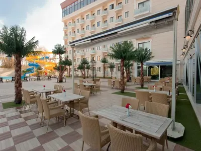 a patio with tables and chairs and a building at Elegance Resort Hotel & SPA Wellness-Aqua in Yalova