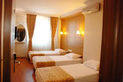 a hotel room with three beds and a window at The Port Hotel in Istanbul