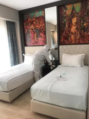 two people in a hotel room making a bed at Mukarnas Taksim Hotel in Istanbul