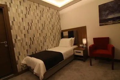 a bedroom with a bed and a red chair at RİVADA HOTEL in Kartepe