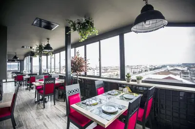 a restaurant with red chairs and tables and windows at RİVADA HOTEL in Kartepe