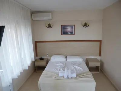 a bedroom with a bed with white sheets and two tables at Istanbul Yildiz Hotel in Marmaraereglisi