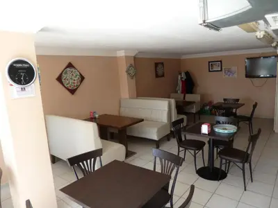 a restaurant with tables and chairs and a clock on the wall at Istanbul Yildiz Hotel in Marmaraereglisi