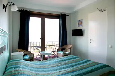 a bedroom with a bed and a view of a balcony at L'isola Guesthouse in Heybeliada