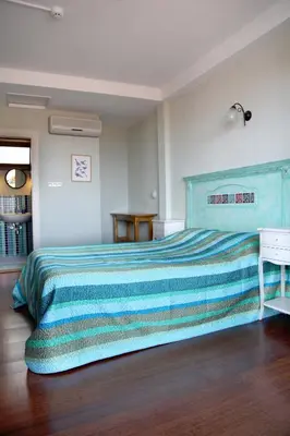 a bedroom with a large bed with a blue bedspread at L'isola Guesthouse in Heybeliada