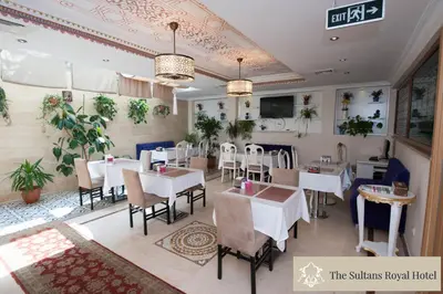 a restaurant with white tables and chairs and plants at Sultans Royal Hotel in Istanbul