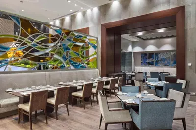 a dining room with tables and chairs and a painting at Hilton Bursa Convention Center & Spa in Bursa