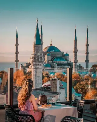 a woman and child sitting at a table with a view of a mosque at Sura Design Hotel & Suites in Istanbul