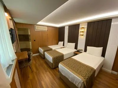 a small hotel room with two beds and a chair at Gumus Palace Gungoren in Istanbul