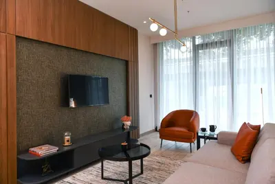 a living room with a couch and a tv on a wall at WestSide Residences by Rotana in Istanbul
