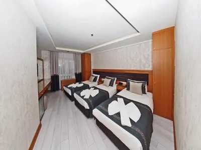 a room with three beds and a flat screen tv at Grand Emir Hotel Old City in Istanbul