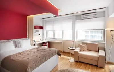 a bedroom with a red wall and a bed and a chair at Nuru Ziya Residences in Istanbul