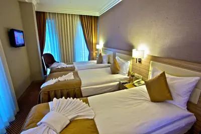a hotel room with three beds and a television at Laleli Emin Old City Hotel in Istanbul