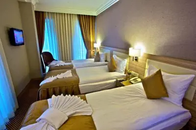a hotel room with three beds and a television at Laleli Emin Old City Hotel in Istanbul