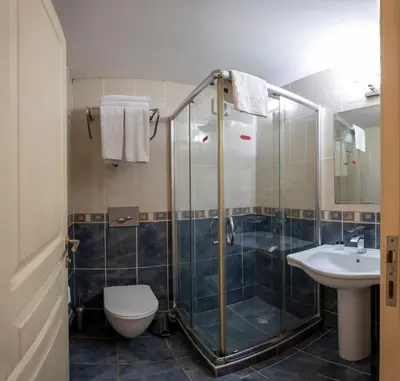 a bathroom with a shower and a toilet and a sink at Tugra Hotel in Istanbul