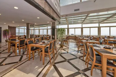a restaurant with wooden tables and chairs and windows at Piya Sport Hotel in Istanbul