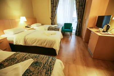 a hotel room with three beds and a television at Artika Hotel in Istanbul