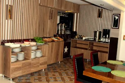 a dining room with a table and a kitchen at Hotel Anibal in Gebze