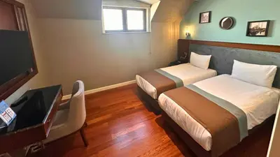a room with two beds and a desk and a television at Grand Durmaz Hotel in Istanbul