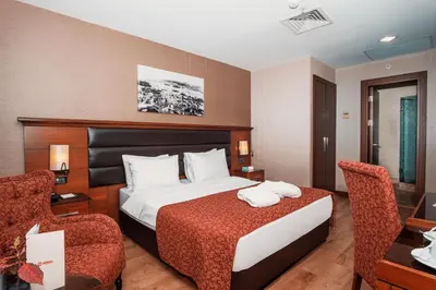 a hotel room with a bed and two chairs at Grand Makel Hotel Topkapi in Istanbul