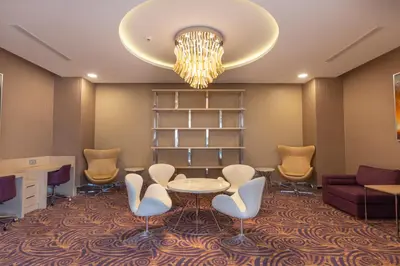 a waiting room with a table and chairs and a chandelier at TRYP by Wyndham Izmit in Kocaeli