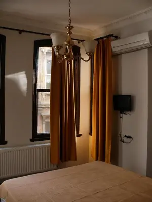 a bedroom with a bed with orange curtains and a window at Budak Residence in Istanbul