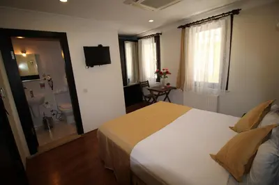 a bedroom with a large white bed and a bathroom at Sultans Hotel in Istanbul