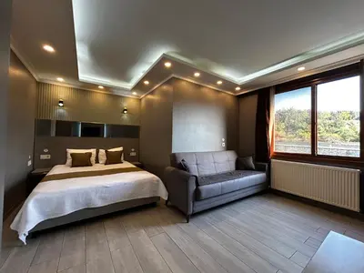 a bedroom with a bed and a couch and a window at Sahrakent Otel Ataşehir in Istanbul