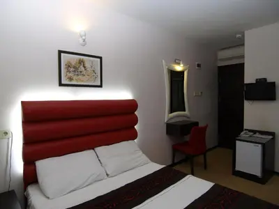 a bedroom with a red headboard with a bed and a desk at Hotel Timya in Istanbul