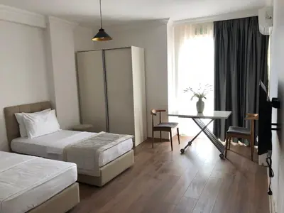 a bedroom with two beds and a desk and a window at Joy Suites in Istanbul