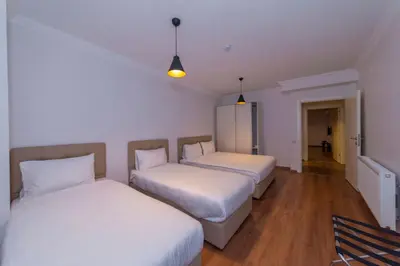 two beds in a room with white walls and wooden floors at Joy Suites in Istanbul