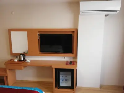 a room with a desk with a tv on a wall at BURSA ŞAHiN HOTEL in Bursa