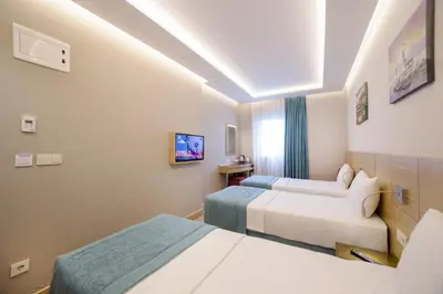 a hotel room with two beds and a tv at Meretto Hotel LALELİ in Istanbul