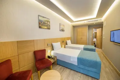 a hotel room with two beds and a chair at Meretto Hotel LALELİ in Istanbul