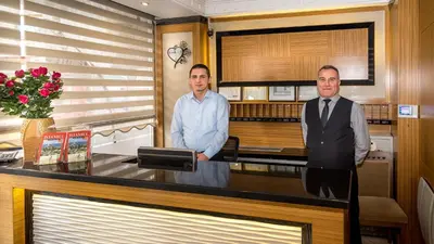 two men standing behind a counter in a room at My Rose Hotel in Istanbul