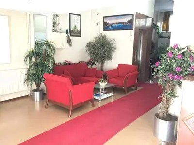 a waiting room with red couches and potted plants at Kadikoy Kervansaray Hotel in Istanbul