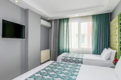 a hotel room with two beds and a flat screen tv at Green Garden Hotel - Bahçelievler in Istanbul