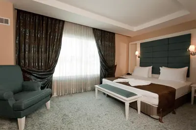 a bedroom with a bed and a chair and a window at Mercia Hotels & Resorts in Buyukcekmece