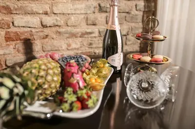 a table with a plate of fruit and a bottle of wine at Panderma Port Hotel in Bandırma