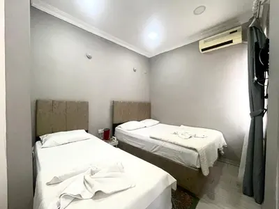 two beds in a small room with white sheets at Hotel Yasmin in Istanbul