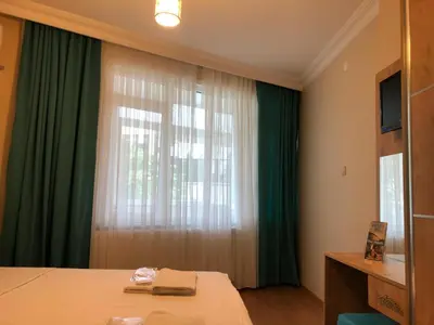 a bedroom with a bed and a window with green curtains at Blue Mosque Apart in Istanbul