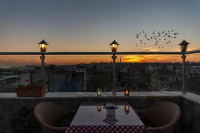 a table on a balcony with birds flying in the sky at Erbazlar Hotel in Istanbul