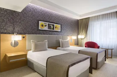 a hotel room with two beds and a chair at Ramada Plaza By Wyndham Izmit in Kocaeli