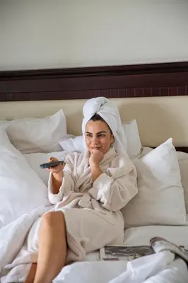 a woman laying in bed holding a remote control at Premier Vista Hotel in Silivri